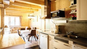 A cozy kitchen with wooden walls, a dining area with a table and chairs, and a built-in microwave.