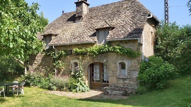 A stone house with a sloped roof, a wooden door, and a small window.
