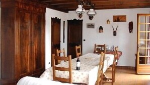Une salle à manger avec une table en bois, des chaises et un lustre.