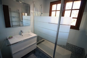 A bathroom with a white sink, mirror, and shower area.