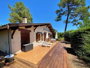 A rustic building with a wooden deck, outdoor seating, and a stone fireplace.