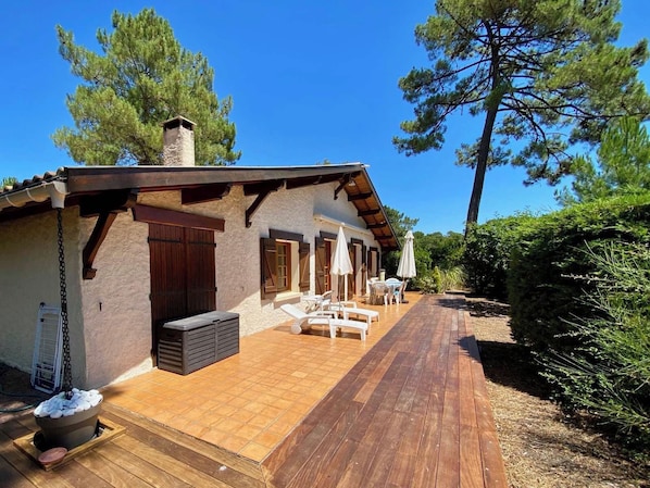 A rustic building with a wooden deck, outdoor seating, and a stone fireplace.