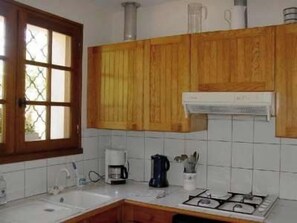 A kitchen with wooden cabinets, a gas stove, a coffee maker, and a window with a view.