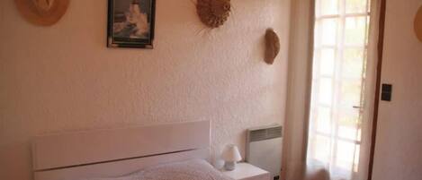 A bedroom with a bed, bedside table, lamp, and a window with curtains.