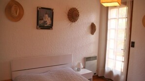 Une chambre à coucher comprenant un lit, une table de chevet, une lampe, un tableau et un objet fixé au mur.