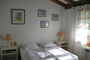 A bedroom with a bed, two bedside tables, lamps, and framed pictures on the wall.
