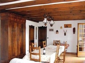 A dining area with a wooden table and chairs, a chandelier, and a wooden cabinet.