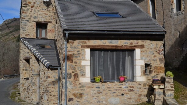 A stone building with a sloped roof, a small window with curtains, and a satellite dish. - CHARMING HOUSE ON THE EDGE OF CEVENNES NATIONAL PARK (Meyrueis)