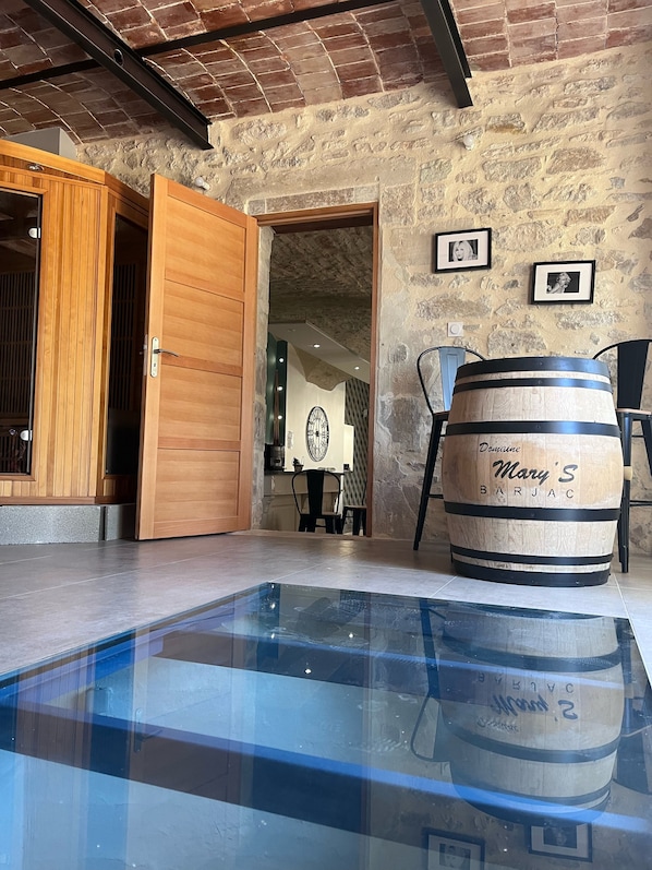A room with a glass-top pool, wooden doors, a stone wall, and a barrel labeled 'Mary's Barjac.' - Gite Mathilde "Between Cèze and Ardèche" 30 BARJAC (Barjac)