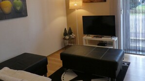 A modern living room with a flat-screen TV, a sofa, a coffee table, and a lamp. - Allgäutraum Apartment No. 1 for 2-4 people in Durach-Weidach (Oberkottern)