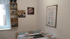 A dining area with a table set for four, chairs, a shelf with kitchen items, and a wall with a motivational poster. - Allgäutraum Apartment No. 1 for 2-4 people in Durach-Weidach (Oberkottern)