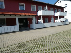 Een rood gebouw met een wit balkon en een pannendak.
