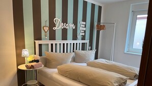 A neatly arranged bedroom with a bed, pillows, a bedside table with a lamp, and a wall with decorative elements. - Allgäutraum Apartment No. 1 for 2-4 people in Durach-Weidach (Oberkottern)