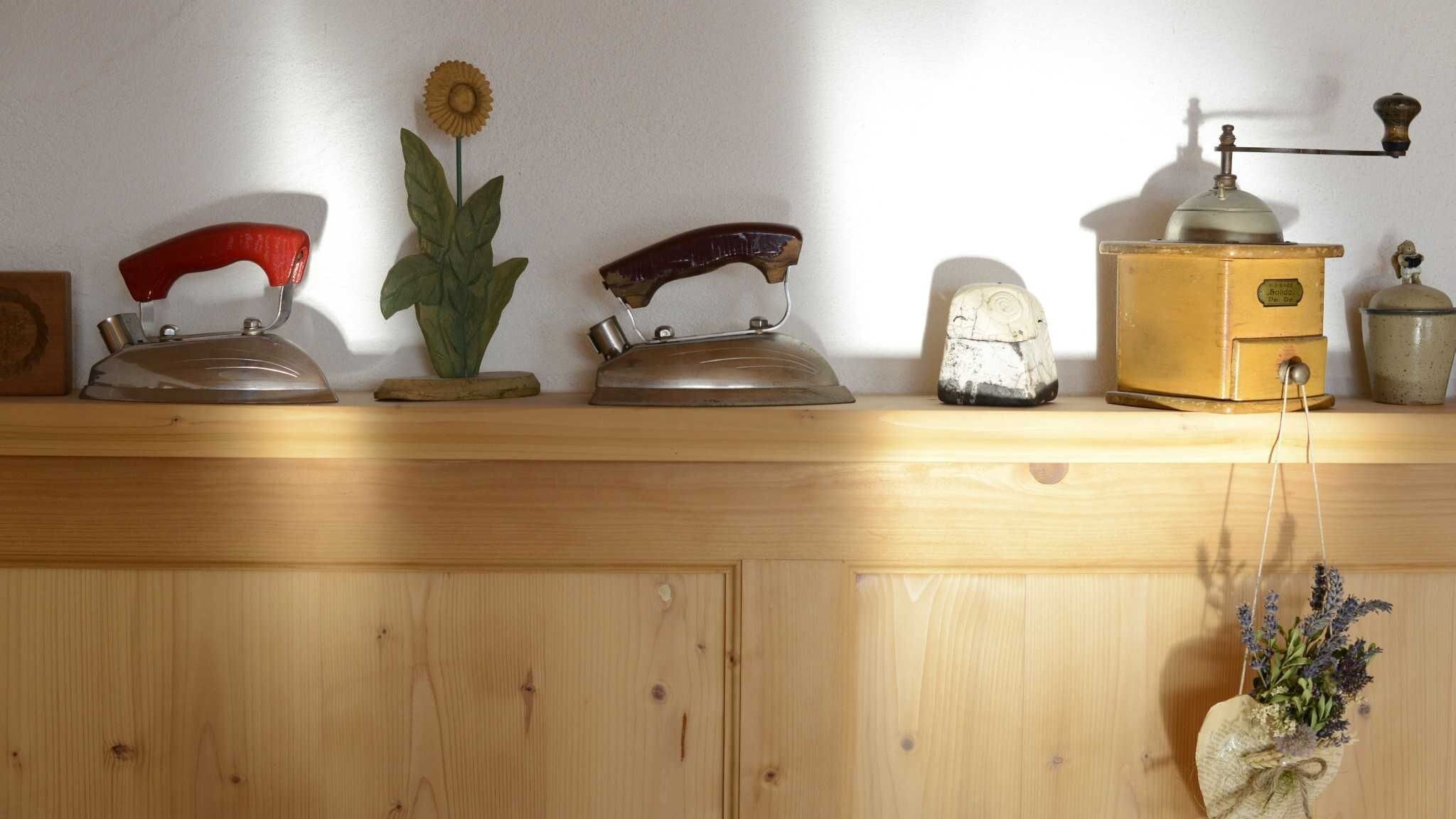 A wooden shelf with vintage kitchen appliances, a flower, and a hanging plant.