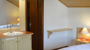 Ein Badezimmer mit Waschbecken, Spiegel und Nachttisch mit Lampe.