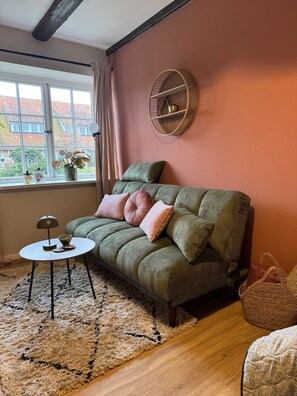 A cozy living room with a green sofa, a round wall shelf, and a small round table.