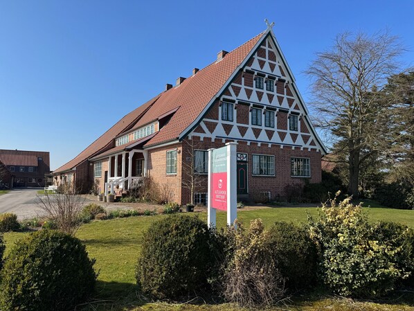 A traditional half-timbered building with a steeply pitched roof, a prominent entrance with a door, and a signboard.
