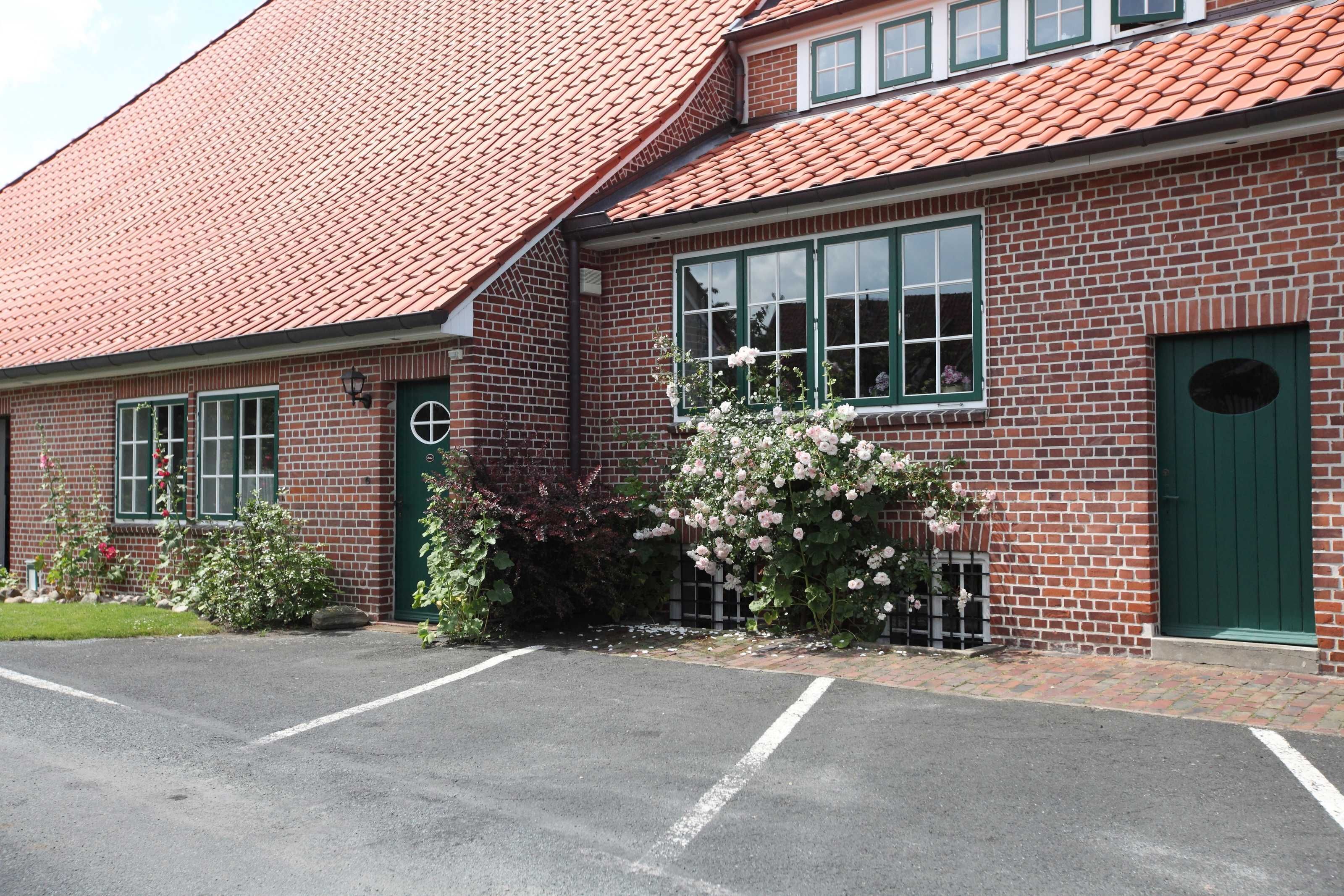 Ein Gebäude aus Ziegeln mit rotem Ziegeldach, grünen Türen und Fenstern.
