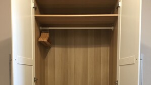 Um closet amplo com portas abertas, com várias gavetas e prateleiras de madeira.