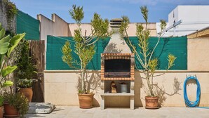A backyard with a swimming pool, a barbecue grill, and potted plants.