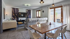A modern living room with a sofa, a dining table with chairs, a TV, and a fireplace.