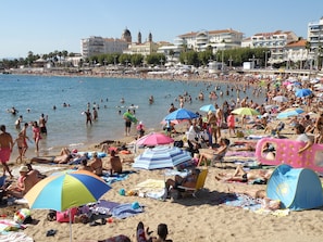 Uma praia cheia de gente tomando sol e nadando.