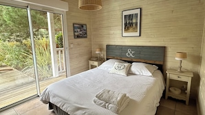 Ein Schlafzimmer mit einem großen Bett, zwei Nachttischen, einer Hängeleuchte und Blick durch eine Schiebetür.