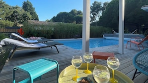 Ein Poolbereich mit Liegestühlen, einem Tisch mit Getränken und Blick auf den Pool und Bäume.