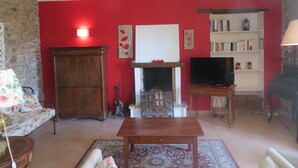 Una sala de estar con chimenea, televisor, estantería y pared de piedra.