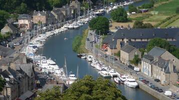 Une ville riveraine dotée d’un port de plaisance rempli de bateaux, de bâtiments historiques en pierre et d’une étroite route longeant le cours d’eau.