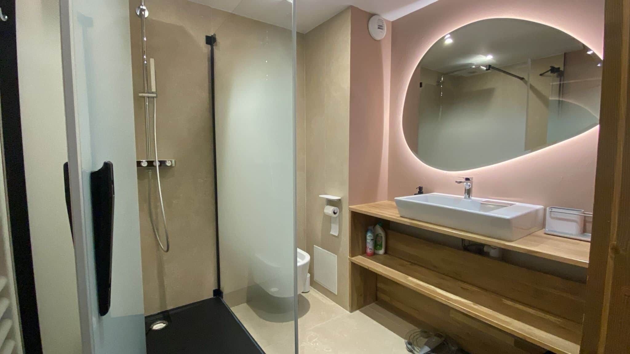 A modern bathroom with a glass shower enclosure, a sink with a mirror, and a toilet.