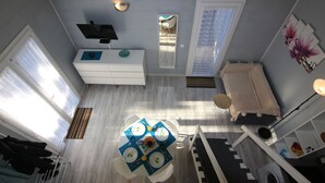 A compact living space with a dining area, a TV mounted on the wall, a sofa, and a window with blinds. - Apartment SOULAC SUR MER 500 m from the beach 3 (Soulac-Sur-Mer)