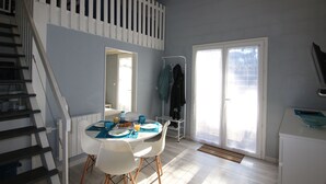 A dining area with a table set for two, a staircase, and a sliding glass door leading outside. - Apartment SOULAC SUR MER 500 m from the beach 3 (Soulac-Sur-Mer)