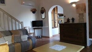 Una sala de estar con un sofá, un televisor, un mueble de madera y una escalera.