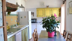 Una cocina con una mesa de comedor, sillas y una planta en maceta.