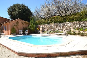 A rectangular swimming pool with a stone wall and a small building in the background. - Seen on the Luberon (Apt)