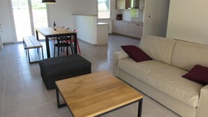 A modern living room with a sofa, a coffee table, and a dining area with a table and chairs.