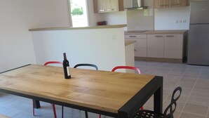 A modern kitchen with a wooden table, chairs, and a bench.