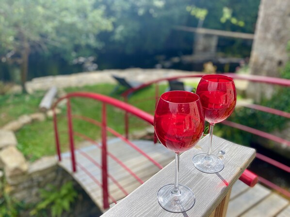 Two red wine glasses on a wooden railing with a red metal railing in the background.