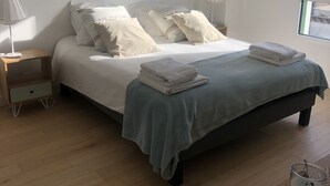 Ein Schlafzimmer mit einem Bett, Kissen, einem Nachttisch, einer Lampe und einem Bild an der Wand.