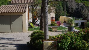 Ein Gebäude mit Ziegeldach, einer Garage mit Dachüberdachung und einem Garten mit Pflanzen und Gartenmöbeln.