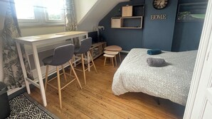 A compact room with a desk, two chairs, a bed, a small table, and a clock on the wall. - !!!Studio less than 50 meters from the sea !!!28 € / Night and 35 € / summer for 2 people (Veulettes-sur-Mer)