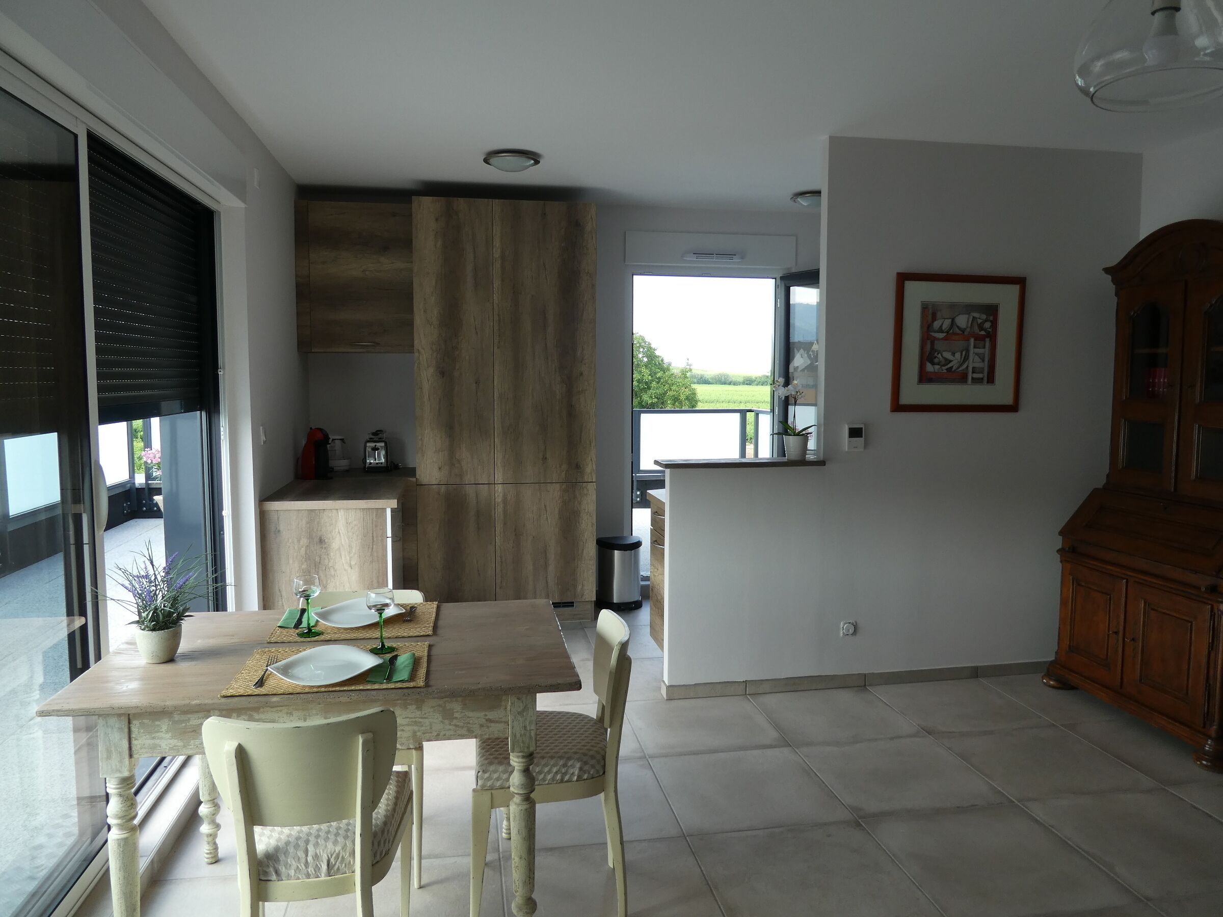 A modern kitchen with a dining area, a large window, and a view of the outdoors.