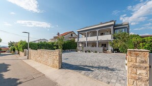 Ein zweistöckiges Wohnhaus mit gepflasterter Auffahrt und Steinmauern.
