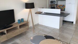 Een knus verblijf met een televisie, lamp, klein tafeltje en kitchenette.