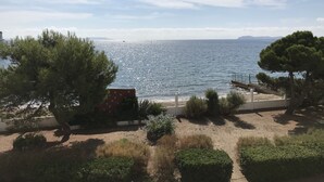 Een kustgezicht met een zandstrand, enkele bomen en een heldere lucht.