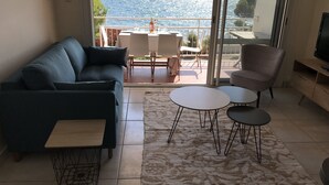 Een woonkamer met een bank, twee bijzettafeltjes, een gestreept fauteuil, en een televisie.