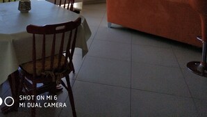 Un ampli saló amb un sofà taronja gran, una taula de dinar amb cadires i vistes al mar a través de grans finestres.