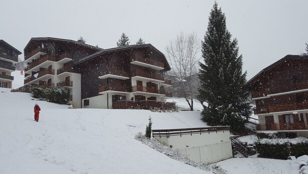 A multi-story building with balconies, surrounded by snow-covered trees and a snowy slope. - Beautiful T2 comfortable near the ski slopes (Saint-Gervais-les-Bains)
