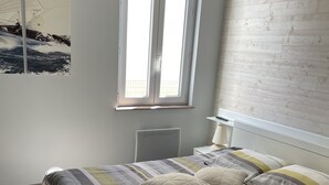 Un dormitorio con una cama, una ventana, un radiador y una pared de madera.